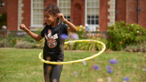 Girl hula hooping on the lawn at Hatchlands Park